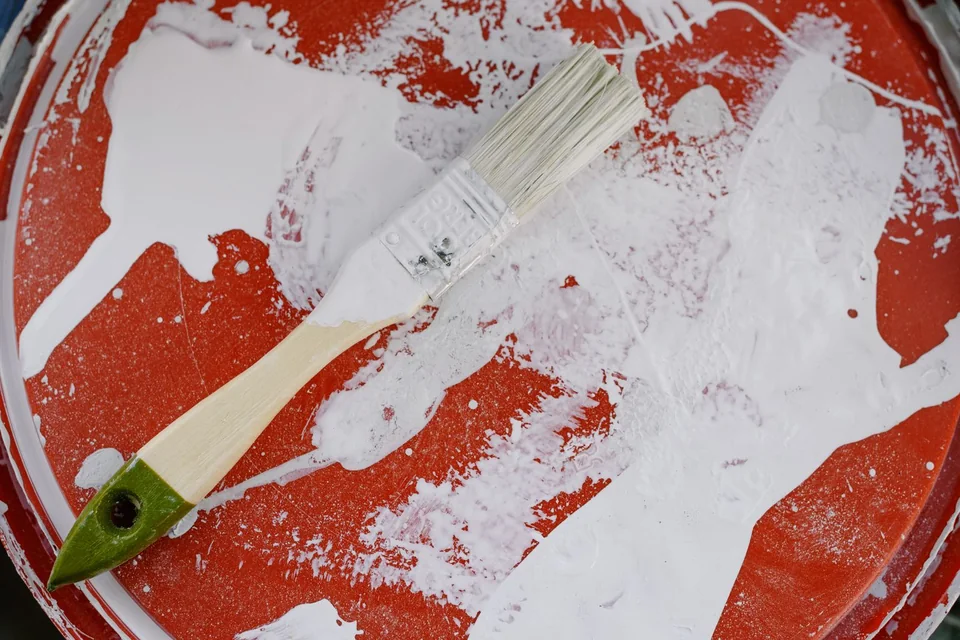 Pinceau posé sur le couvercle d'un pot de peinture blanche