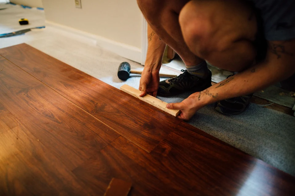 Poseur ajustant une lame de parquet sur une sous-couche