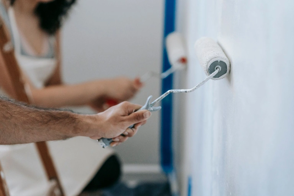 Deux rouleaux appliquant une peinture blanche sur un mur